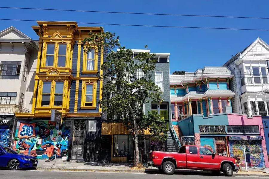 Vista de coloridos edificios en Haight Street con autos estacionados a lo largo de la calle. San Francisco, California.